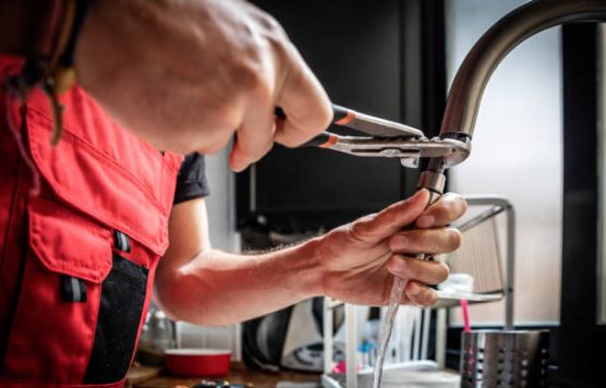 Repairman using adjustable pliers to fix kitchen faucet. Concept of repair.